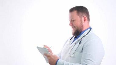 Beyaz önlüklü, sakallı, gülümseyen doktor günlük girişi yapıyor, yakın plan, kopyalama alanı.