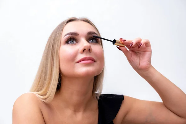 Kopfschuss einer Frau mit hellem Make-up, die Mascara auf die Wimpern aufträgt. — Stockfoto