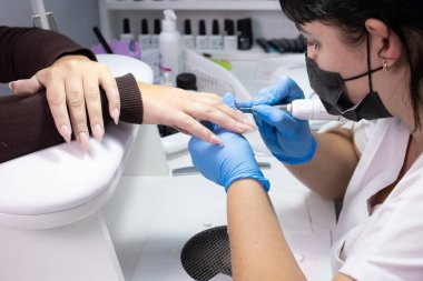 Master manikür salonunda çivi jel üzerinde vernik çizim uygular