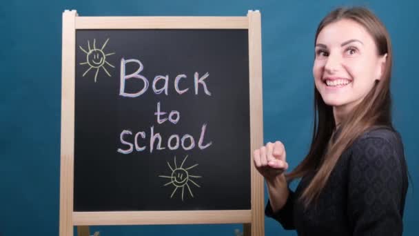 Terug naar school, een lerares met bril staat naast het schoolbord en danst — Stockvideo