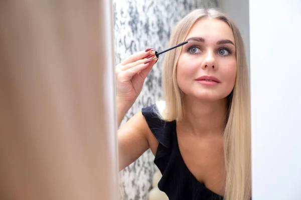 Femme se maquille, peint ses cils, pour une soirée devant un miroir — Photo