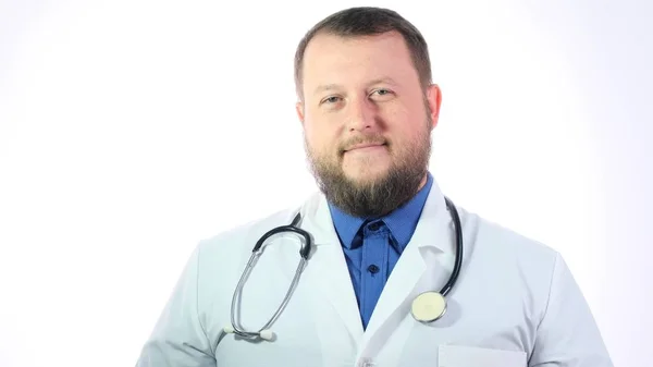 Portré egy szakállas mosolygós férfi orvos fehér kabátban fonendoszkóppal a nyakán, egészségügyi és orvosi koncepció. — Stock Fotó