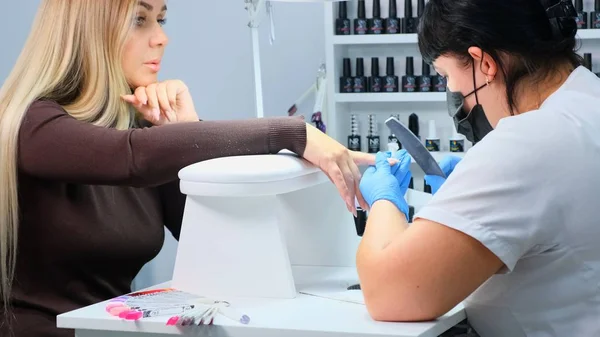 Nizhnevartovsk, Oroszország - augusztus 12, 2019: Manicurist files a nail file to a client. Manikűrözés, körömhosszabbítás. — Stock Fotó