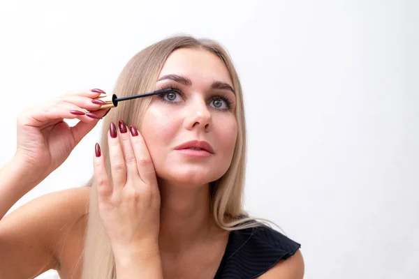 Headshot de femme avec un maquillage lumineux appliquant mascara sur les cils . — Photo