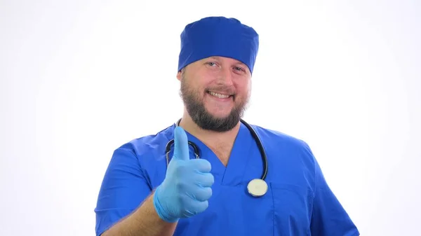 Szakállas mosolygós férfi orvosi dolgozó, hüvelykujjal felfelé táblát mutat. — Stock Fotó