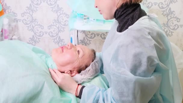 Medelålders kvinna 50 får en lyft injektion av en injektion av hyaluronsyra i ansiktet av en läkare kosmetolog. Kosmetiskt förfarande. — Stockvideo