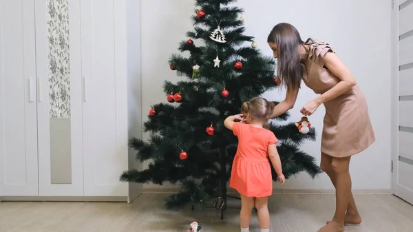 Rodina, zimní dovolená a lidé koncept - šťastná matka a dceruška zdobí vánoční stromeček doma — Stock fotografie