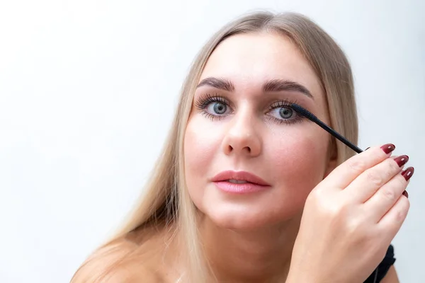 Portrait de beauté de fille avec un maquillage nu parfait. Peindre les cils avec du mascara. Retourné. Salon de beauté. Tête et épaules, studio, intérieur . — Photo