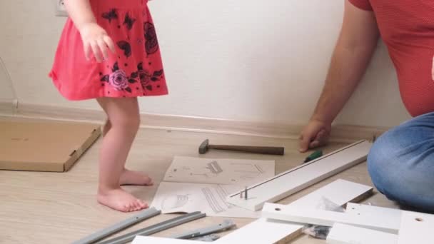 Papà uomo raccoglie mobili bianchi per la casa. La figlia aiuta papà a raccogliere mobili. primo piano — Video Stock