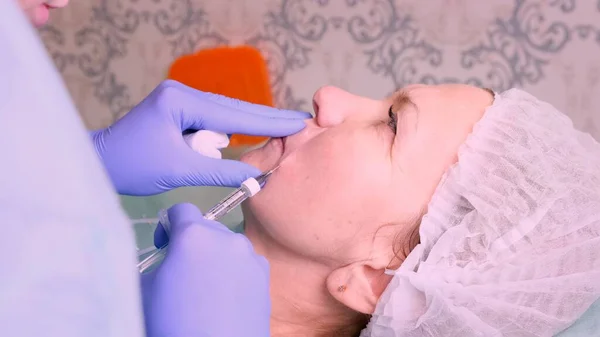 Aumento delle labbra. Medico estetista che esegue una procedura di bellezza alle labbra femminili con una siringa. Donna anziana. Aumento delle labbra . — Foto Stock