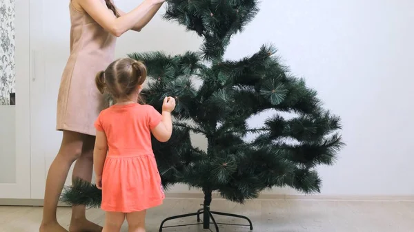 Feliz mamá y su hija recogen el árbol de Navidad en casa. Preparación de Navidad y Año Nuevo — Foto de Stock