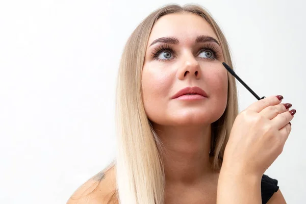 Beautiful blonde woman paints eyelashes. Beautiful female face. Makeup Read More Beauty girl with perfect skin. Makeup in progress