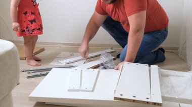 Babam beyaz ev eşyaları topluyor. Kızı babanın mobilya toplamasına yardım ediyor..