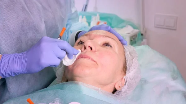 Il dottore cosmetologo prepara una faccia di donne a un'iniezione cosmetica, iniezioni di acido ialuronico. Una donna in un salone di bellezza. clinica di chirurgia plastica — Foto Stock