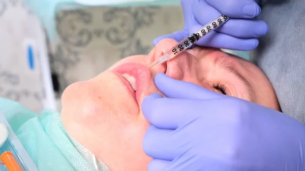 Il cosmetologo esegue una procedura per aumentare le labbra di una donna in un salone di bellezza. cura della pelle. Iniezioni cosmetiche . — Foto Stock