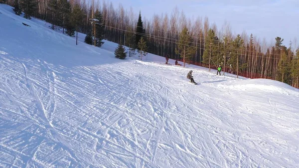 Vista superior de un snowboarder deslizándose desde la cima de una montaña en un día soleado de invierno. El concepto de snowboard . — Foto de Stock