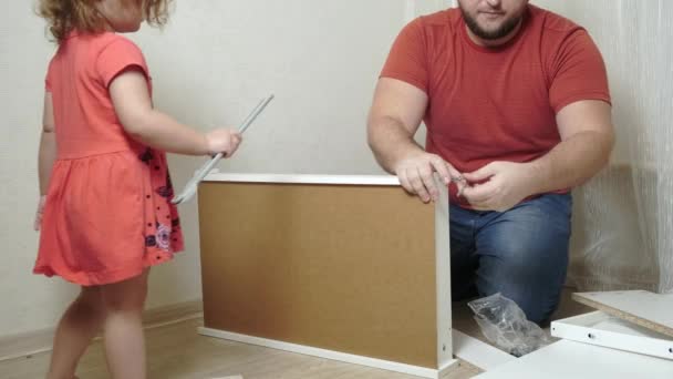 Pappa man samlar vita hemmöbler. Dottern hjälper pappa att samla möbler. närbild — Stockvideo