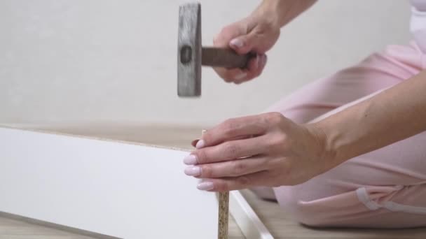 Mulher recolhe móveis brancos em casa usando um martelo. Close-up . — Vídeo de Stock