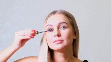 Göz makyajı. Lash 'e Mascara süren güzel bir kadın. Gülümseyen Kadın Kirpiklerini Fırçayla Yapıyor.