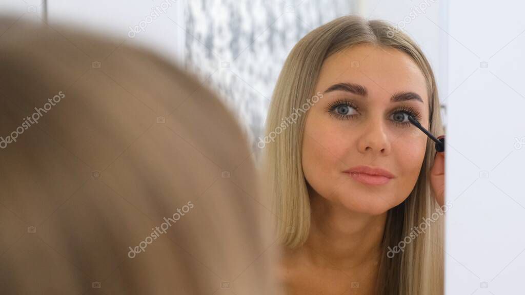 Woman Applying Make Up In Front Of A Mirror.
