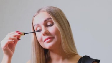 Göz makyajı. Lash 'e Mascara süren güzel bir kadın. Gülümseyen Kadın Kirpiklerini Fırçayla Yapıyor.