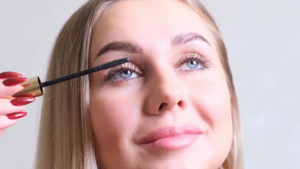 Make-up. Krásná žena nanáší řasenku na řasy. Usmívající se samice tvořící řasy make-up štětcem. — Stock video