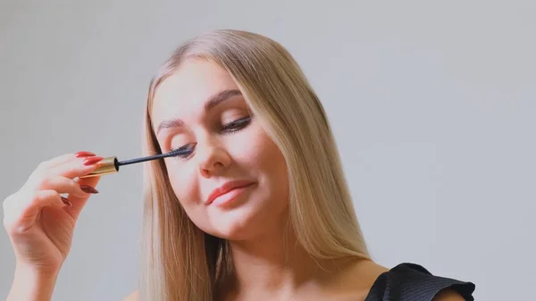 Maquillaje de ojos. Hermosa mujer aplicando máscara en las pestañas. Hembra sonriente haciendo maquillaje de pestañas con cepillo. — Foto de Stock