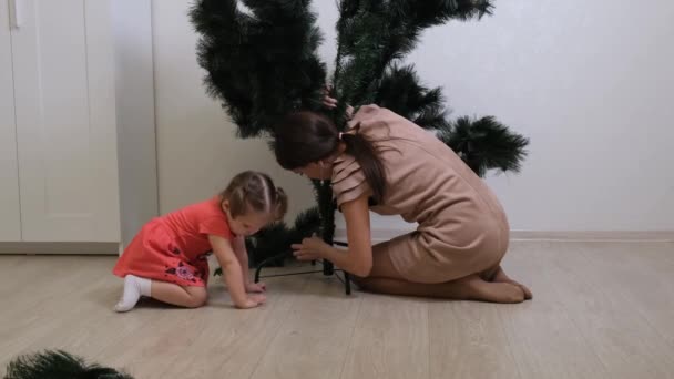 Щаслива мати і маленька дочка збирають ялинкові прикраси вдома. підготовка до Різдва і Нового року. сім'я, зимові канікули і концепція людей — стокове відео