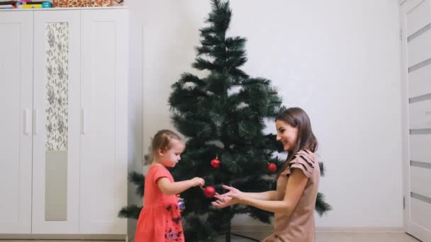 Madre felice e piccola figlia che decorano l'albero di Natale a casa. concetto di famiglia, vacanze invernali e persone . — Video Stock