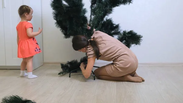 Happy mother and little daughter collect christmas tree decorations at home. preparation for christmas and new year. family, winter holidays and people concept — 스톡 사진