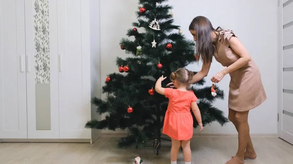 Feliz madre e hija pequeña decorando el árbol de Navidad en casa. concepto familia, vacaciones de invierno y personas . — Foto de Stock