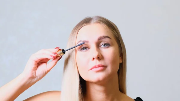 Das kaukasische Model bemalt Wimpern mit Wimperntusche. Make-up Frau — Stockfoto