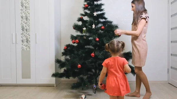 Feliz Navidad y Felices Fiestas. Mamá y su hija decoran el árbol de Navidad en el interior. La mañana antes de Navidad . — Foto de Stock