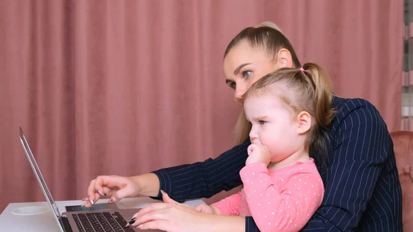 Giovane bella bionda e la sua affascinante figlioletta stanno facendo shopping online con un computer portatile e carta di credito. Shopping nel negozio online . — Foto Stock