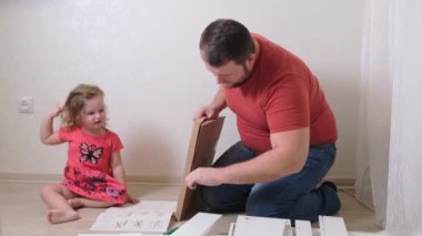 Babam beyaz ev eşyaları topluyor. Kızı babanın mobilya toplamasına yardım ediyor..