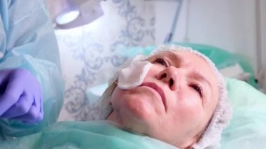 50 yaşındaki orta yaşlı bir kadın, bir doktor kozmetolojist tarafından yüzüne hiyalüronik asit enjekte ediliyor. Kozmetik prosedürü. yakın plan