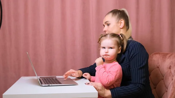 工作的妈妈在总公司工作。快乐的母亲和女儿笑着。成功的女人和可爱的孩子使用笔记本电脑。自由职业者的工作场所。女商人。这并不容易，但她能胜任这项任务 — 图库照片