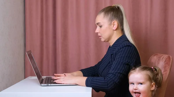 Working mom works from home office. Happy mother and daughter smiling. Successful woman and cute child using laptop. Freelancer workplace. Female business. It is not easy but she is up to the task