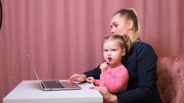 A mãe trabalhadora trabalha em casa. Mãe e filha felizes sorrindo. Mulher de sucesso e criança bonita usando laptop. Local de trabalho freelancer. Negócios femininos. Não é fácil, mas ela está à altura da tarefa — Vídeo de Stock