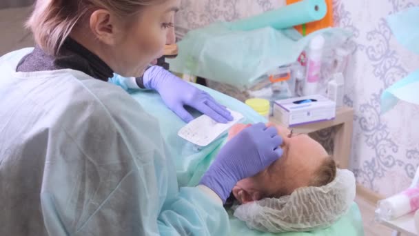 Женщина средних лет 50 лет получает подъемную инъекцию гиалуроновой кислоты в лицо от врача-косметолога. Косметическая процедура . — стоковое видео