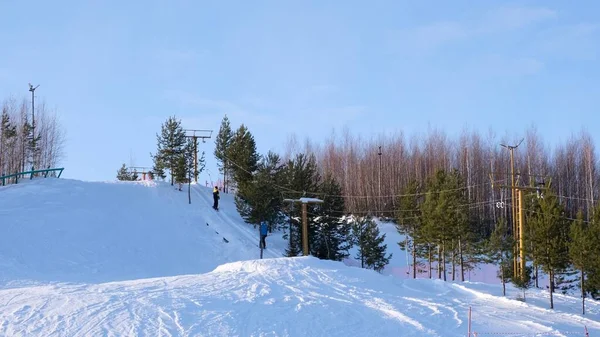 Гірськолижні витяги тривають яскраво зимовий день. Лижники та сноубордисти піднімаються на гору за допомогою підйомника — стокове фото