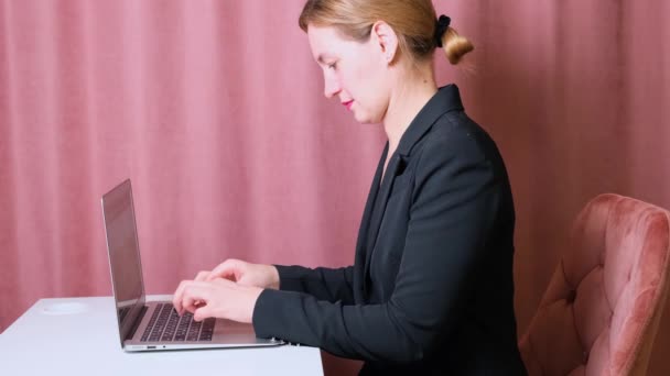 Allvarlig kvinnlig sekreterare skriva på en bärbar dator sitter vid ett bord på sin arbetsplats. — Stockvideo