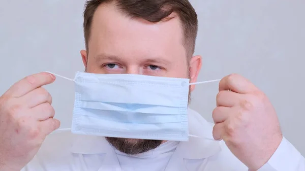O homem barbudo põe uma máscara protectora. Conceito de higiene. prevenir a propagação de germes e bactérias e evitar a infecção com o vírus da coroa — Fotografia de Stock