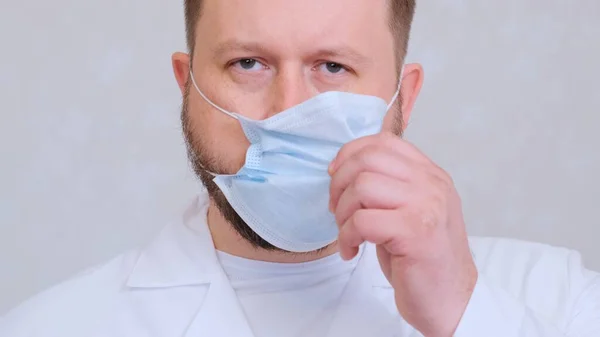 Vousatý lékař si se smutným výrazem sundá ochrannou masku. Tohle je konec. Hygienický koncept. zabránit šíření bakterií a bakterií a vyhnout se infekci korunním virem — Stock fotografie