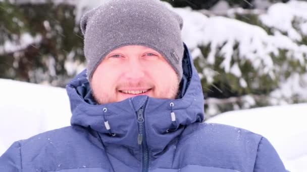 Mâle avec une barbe en bleu vêtements d'hiver est de boire du thé chaud ou du café à l'extérieur par une journée ensoleillée d'hiver, tomber de la neige . — Video