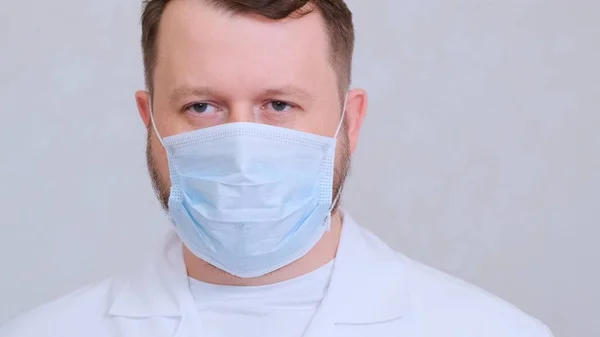 Egy férfi védő maszkban és fehér ingben a kamerába néz, közelről. Higiéniai koncepció. megakadályozza a baktériumok és baktériumok terjedését, és elkerüli a koronavírussal való fertőződést. másolás helye — Stock Fotó