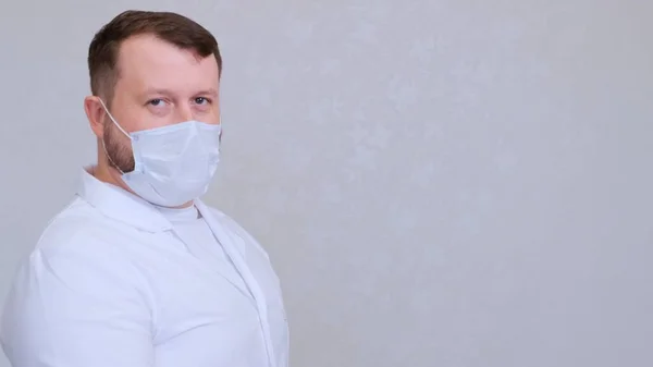 Άντρας με προστατευτική μάσκα και λευκό πουκάμισο κοιτάζει την κάμερα, από κοντά. Η έννοια της υγιεινής. πρόληψη της εξάπλωσης μικροβίων και βακτηρίων και αποφυγή μόλυνσης με τον ιό της κόμης. αντίγραφο χώρου — Φωτογραφία Αρχείου