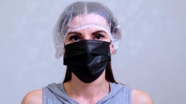 Tek kullanımlık şapkalı kadın hasta siyah koruyucu maskeyi çıkarıyor. Hijyen konsepti. Mikrop ve bakterilerin yayılmasını önler ve taç virüsü bulaşmasını önler.