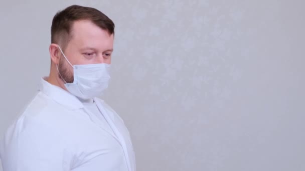 Male in a protective mask and a white shirt looks at the camera, close-up. Hygiene concept. prevent the spread of germs and bacteria and avoid infection with the crown virus. copy space — Stock Video