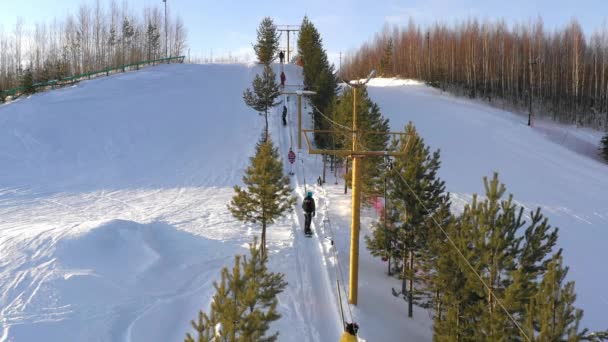 Aydınlık kış gününde kayak kaldırır. Kayakçılar ve snowboardcular kayak asansörüyle dağa tırmanırlar. — Stok video